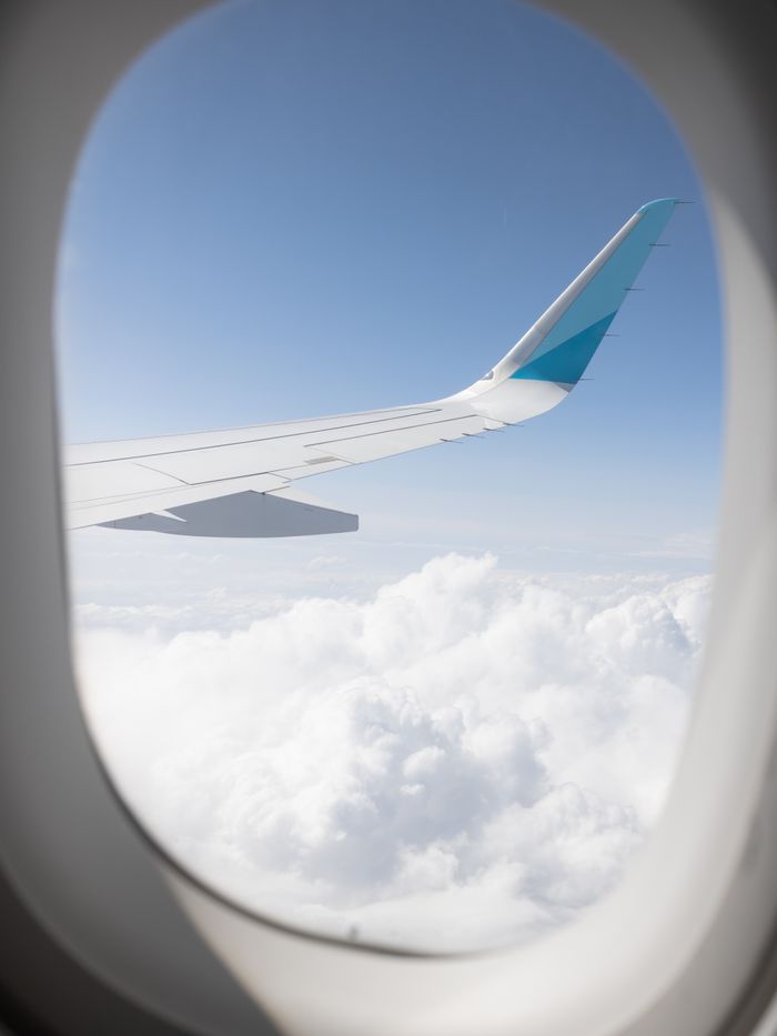 Captivating view of an airplane wing above fluffy clouds through the window, showcasing a serene sky.